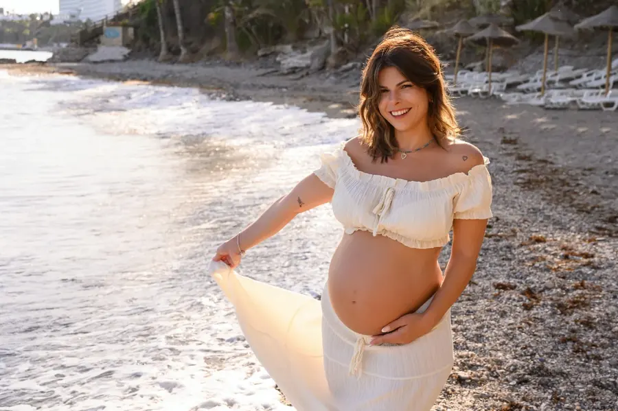 Mano sobre la barriga de embarazo junto al mar, fotografiada por Manuela Monteleone